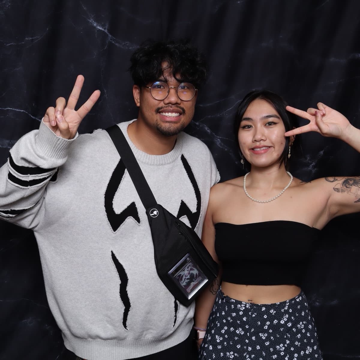 two friends flashing peace signs at the booth